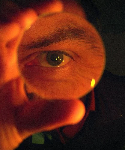 Man's eye focused looking through a magnifying glass