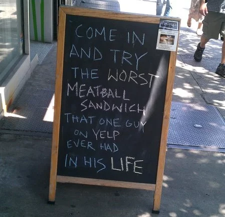 A humorous chalkboard a restaurant put up in response to a negative Yelp review